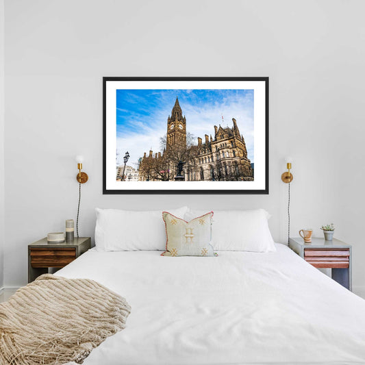 This is a photographic print of the Manchester Town Hall. The photo shows the front of the building with the clock tower. You can see a blue sky with some clouds.